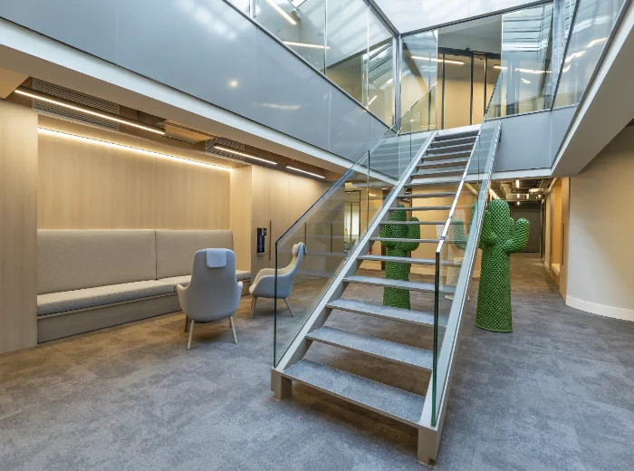 Escala interior amb baranes de vidre en un espai modern i lluminós