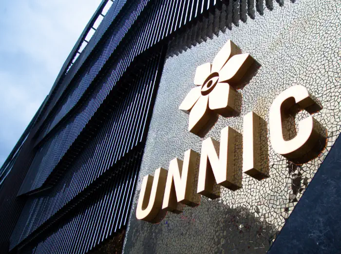 Rètol lluminós d’UNNIC instal·lat en una façana contemporània amb acabats metàl·lics i il·luminació arquitectònica.