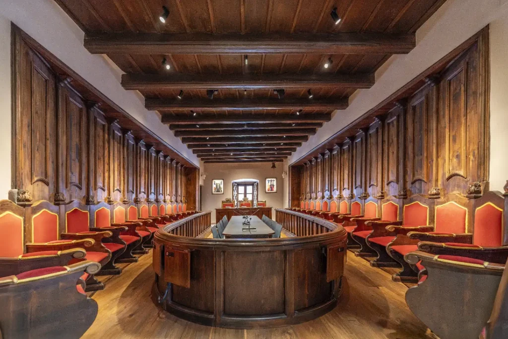 Sala de sessions de la Casa de la Vall a Andorra la Vella amb mobiliari històric, sostres de fusta i arquitectura patrimonial.