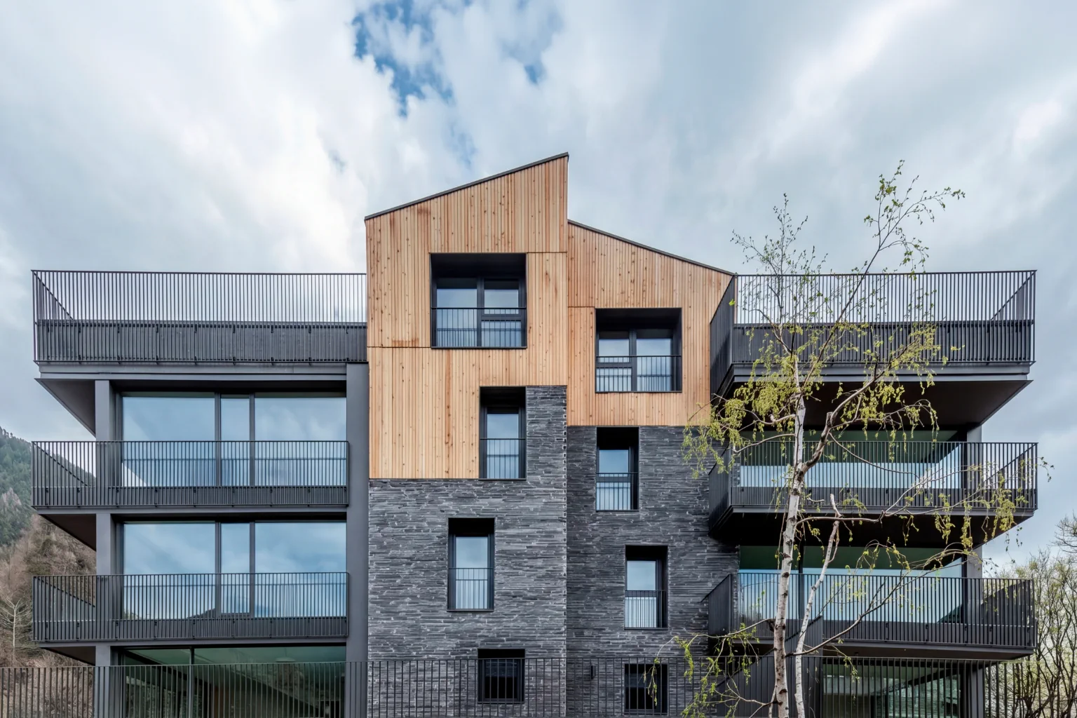Façana principal d’edifici residencial modern amb terrasses panoràmiques i acabats de pedra i fusta a Ordino
