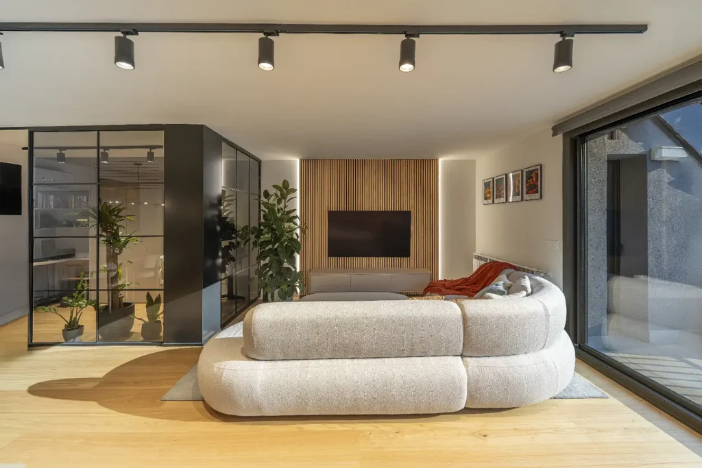 Sala d'estar amb sofà corbat, panell de fusta i accés a terrassa de l'habitatge Estany Blau, Andorra la Vella