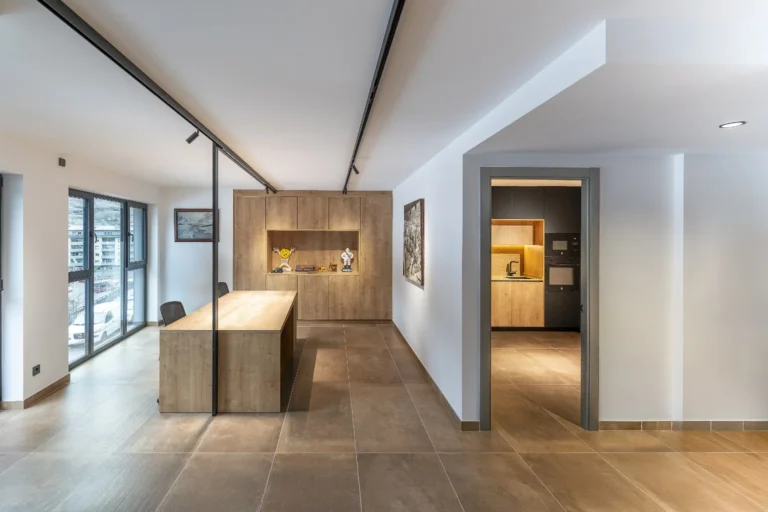 Interior d'oficina de l'Edifici SAI amb mobiliari de fusta, illa central i cuina office integrada al fons.